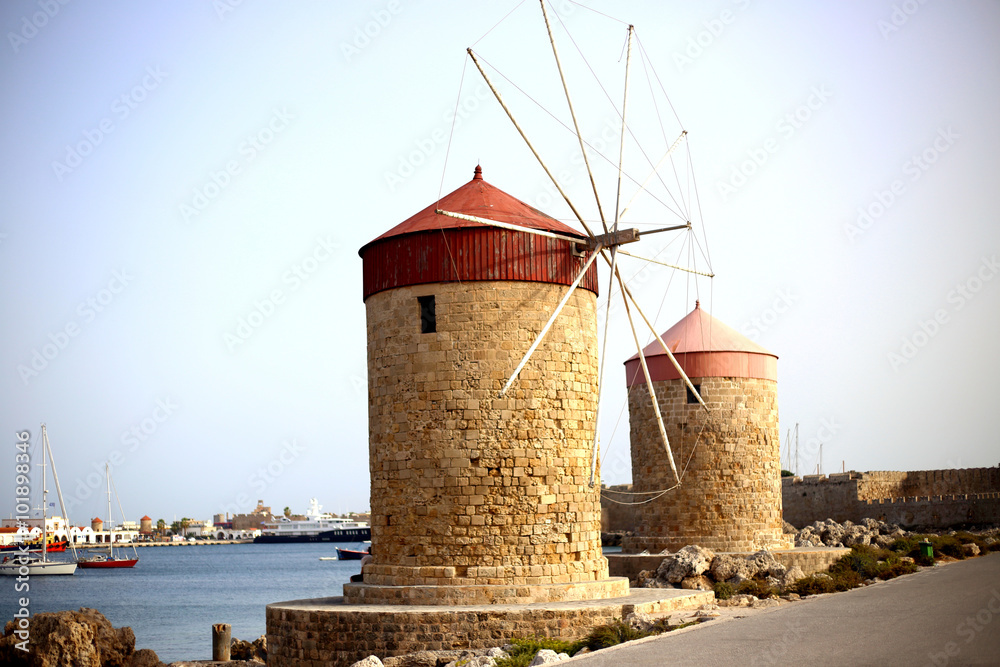windmill. Windmills in the Mandraki port of Rhodes, Greece. Photo from port of iconic windmills near medieval old town of Rhodes island, Dodecanese, Greece . The Mandraki harbor in Rhodes town, Greece