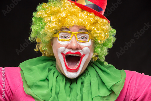 Cheerful funny clown in a hat with a big candy