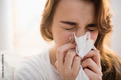 Woman blowing her nose on couch