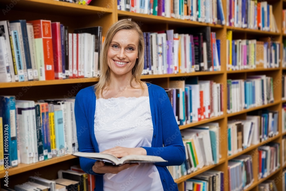 Happy female student reading a book in the library Happy female student reading a book in the library