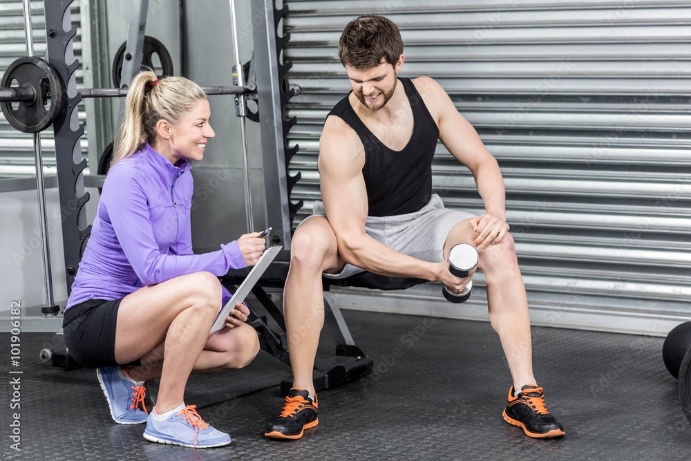 Obraz premium Kobieta trener pomaga człowiekowi z hantlami