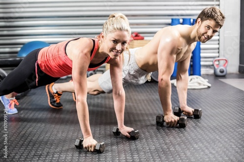 Couple doing push up with dumbbells 