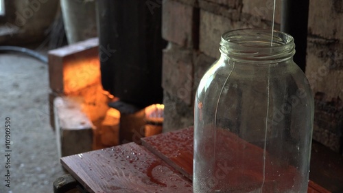 Final stage of illegal hooch alcohol production in rural farm room. Strong drink liquid flow in glass jar. Static closeup shot. 4K
