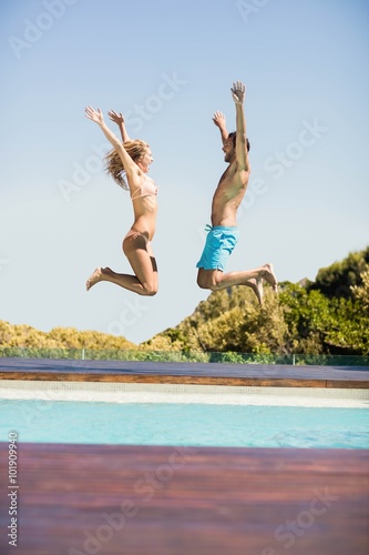 Happy couple jumping in the pool