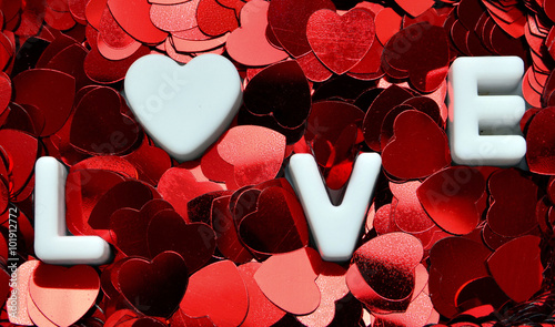 Fototapeta Naklejka Na Ścianę i Meble -  The word LOVE spelled on decorative hearts confetti background.