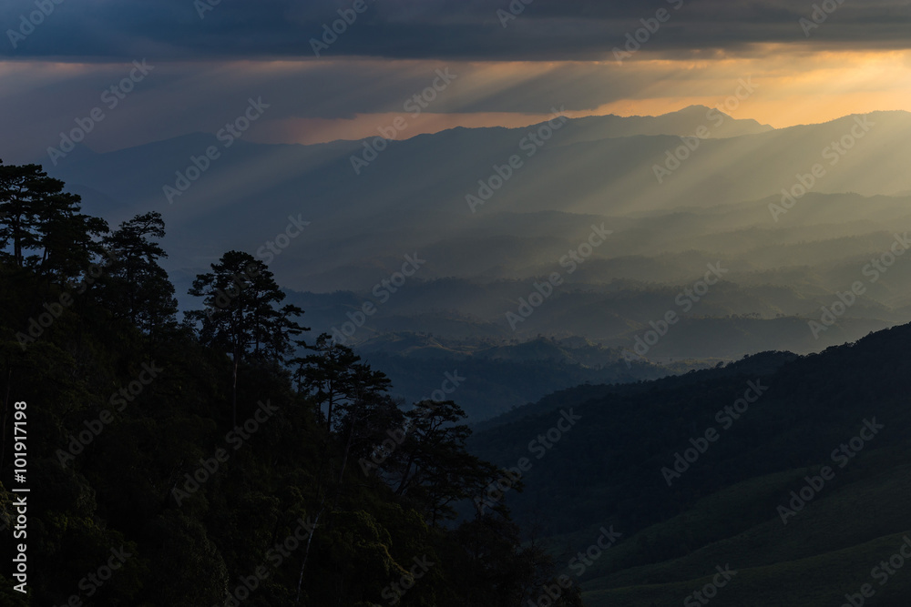 sun rays breaking through the clouds over a mountain landscape a