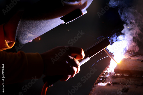 Fotografie Close-up worker with protective mask welding metal.