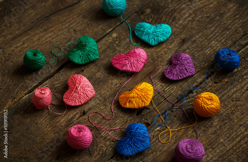 Multicolored Hearts with a balls of thread on old shabby wooden