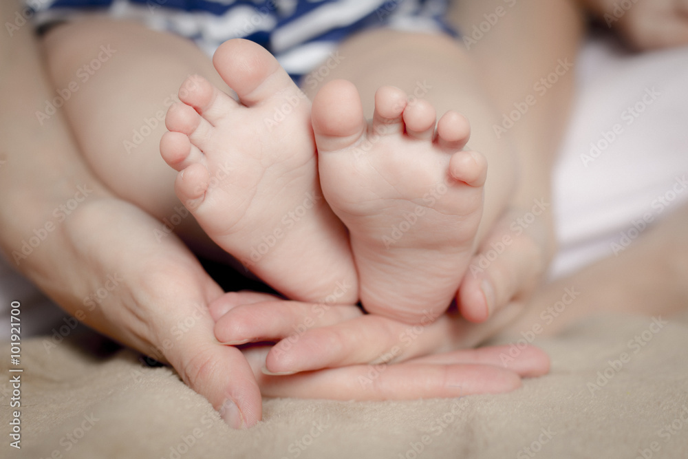 Gentle touch. Woman holding tiny baby feet in her hands Gentle touch. Woman holding tiny baby feet in her hands