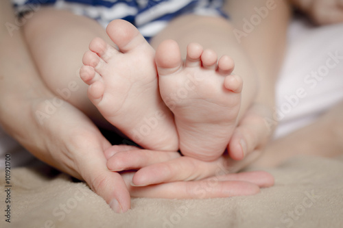 Gentle touch. Woman holding tiny baby feet in her hands © ppicasso