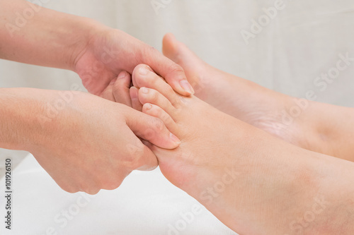 Therapist doing reflexology massage on woman foot in day spa