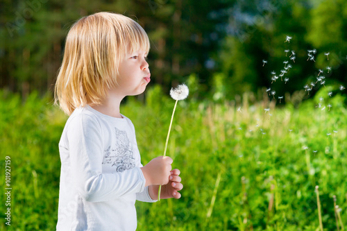 Cute blond little boy blowing a dandelion © Mila May