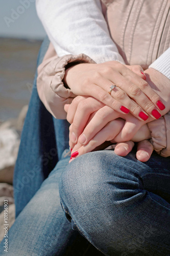 Loving couple holding hands with weddind ring and red nails