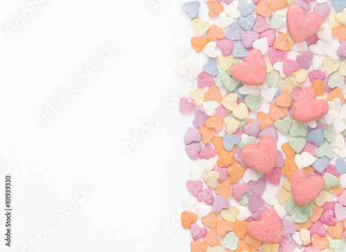 Background on Valentine's Day. Colorful sprinkling sugar confectionery and biscuits shaped heart. Empty space for text. White background.