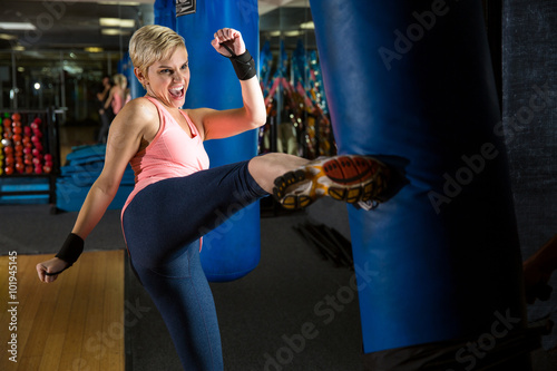 Woman kicks bag intense kickboxing muay thai training amateur beginner class