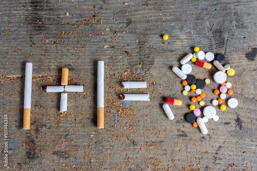 Cigarettes and pills on a wooden surface photo