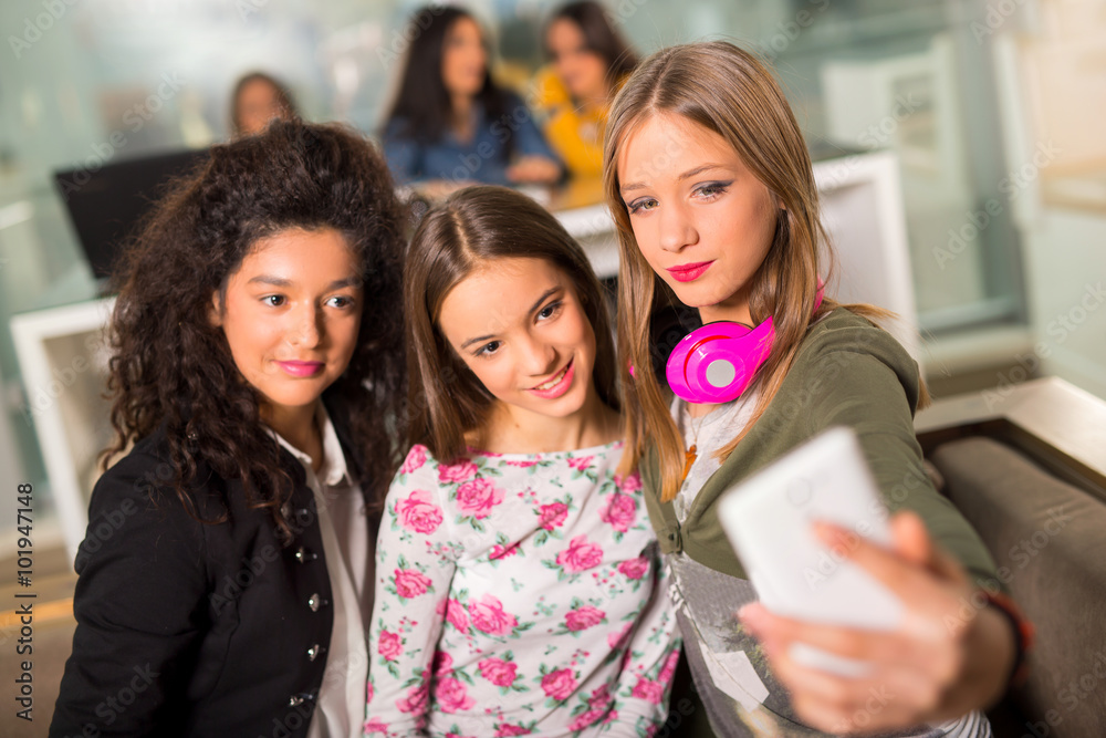 Teenager girls hanging out together in a coffee shop, taking selfie with smartphone Teenager girls hanging out together in a coffee shop, taking selfie with smartphone