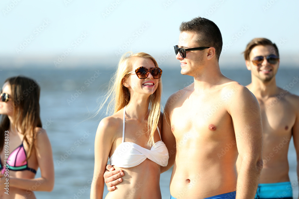 Happy couple and their playful friends relaxing at the beach, outdoors Happy couple and their playful friends relaxing at the beach, outdoors