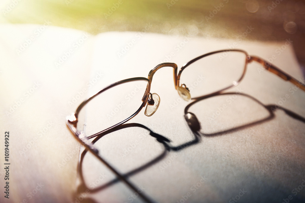 Opened book and eyeglasses on it, close up Opened book and eyeglasses on it, close up