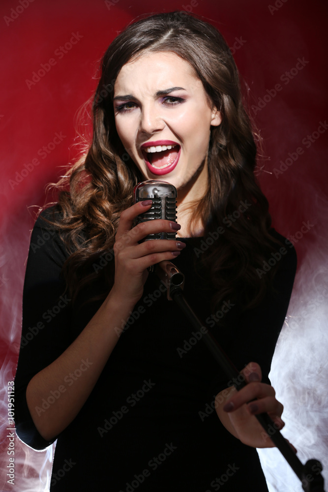 Attractive singing woman in white dense smoke on red background, close up Attractive singing woman in white dense smoke on red background, close up