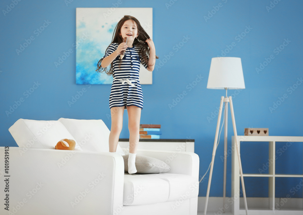 Φωτογραφία Cute little girl singing in a wooden pencil and has fun in the modern room