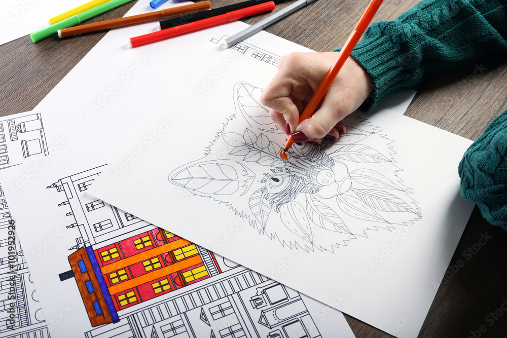 Female hand painting anti stress colouring with orange felt pen Female hand painting anti stress colouring with orange felt pen