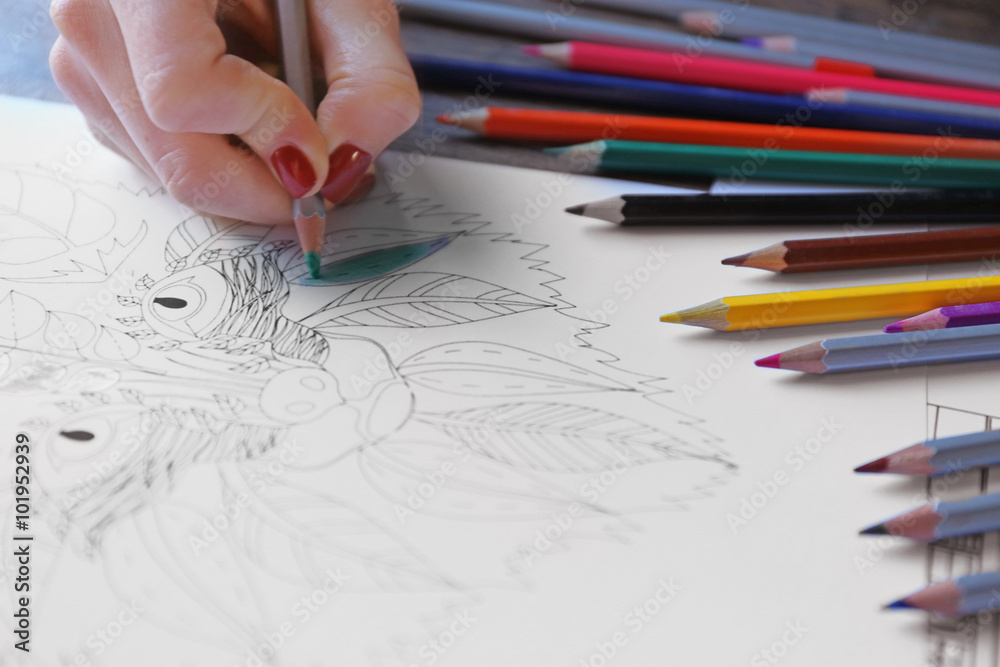 Female hand painting anti stress colouring with green pencil Female hand painting anti stress colouring with green pencil
