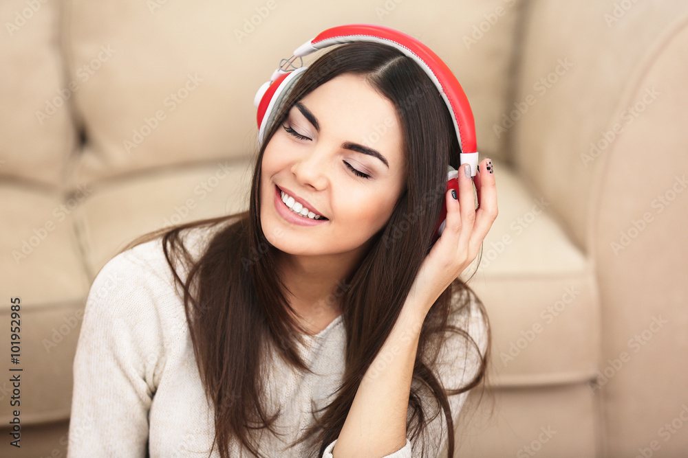 Φωτογραφία Happy young woman with headphones listening to music at home
