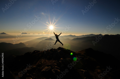 Springender Sportler am Berg bei Sonnenaufgang photo