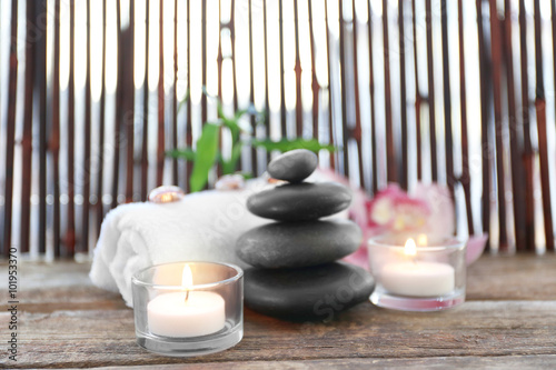 Spa stones with towel, candles, bamboo and pink orchid on wooden background