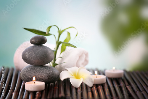 Spa stones with towel  candles and tropical flower on blurred background