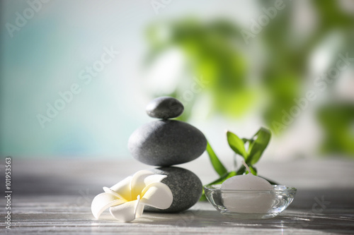 Spa stones with tropical flower, bamboo and candle on blurred background