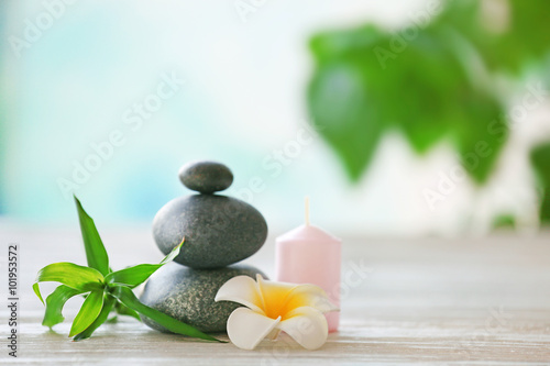 Fototapeta Naklejka Na Ścianę i Meble -  Spa stones with candle, bamboo and tropical flower on blurred background