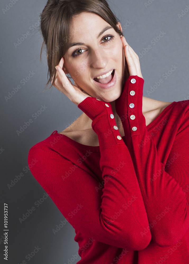 Φωτογραφία female model laughter portrait - closeup of thrilled 20s girl laughing, wearing red winter sweater over gray background, studio shot