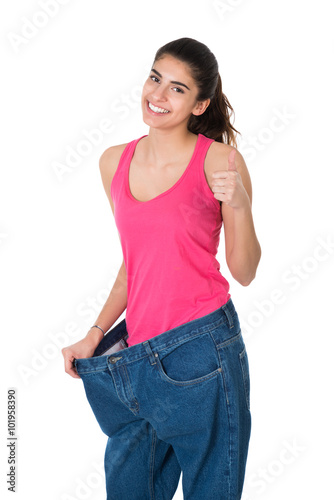Woman Gesturing Thumbs Up While Showing Her Old Jeans