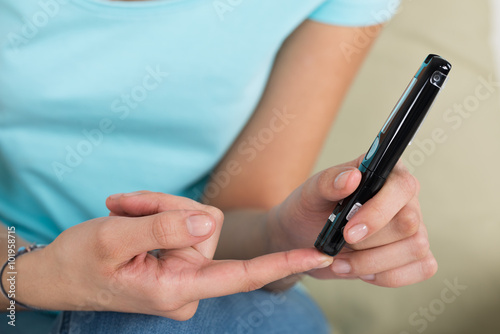 Woman Using Glucometer To Check Blood Sugar Level