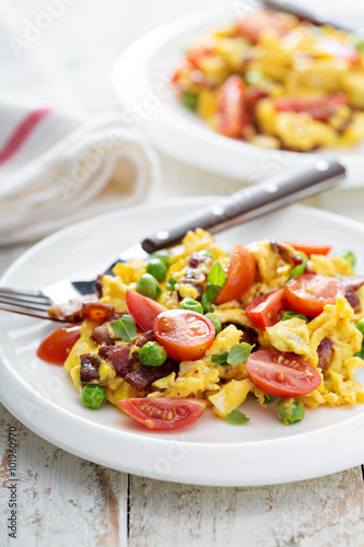 Scrambled eggs with peas, bacon and tomatoes