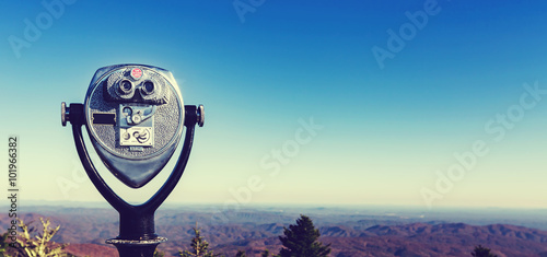 Coin-operated binoculars looking out over a mountain landscape photo