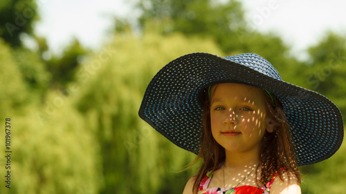 Cute little girl in big hat pretending to be lady