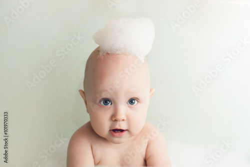 Маленький мальчик младенец в ванной с пеной на голове 