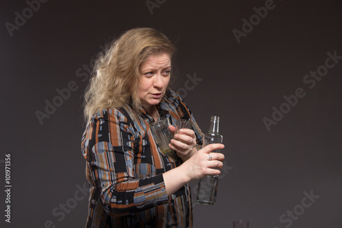 Female alcoholism. Woman aged one drinks vodka from a bottle and