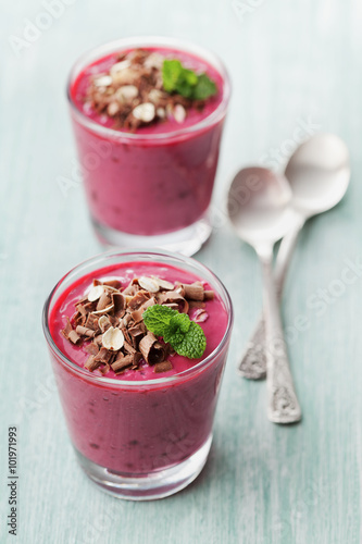 Healthy breakfast of berry smoothie, dessert, yogurt or milkshake with chocolate and oats decorated green mint leaves on rustic table, detox and diet food