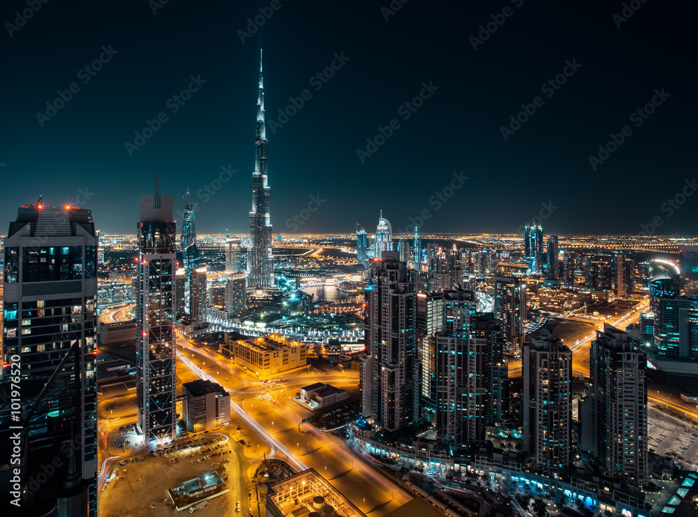 Fantastic rooftop view of Dubai's modern architecture by night with illuminated skyscrapers.