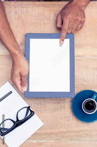Person holding on digital tablet by coffee and document