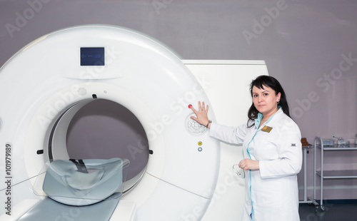 A female doctor pushing control button on CT scanner
