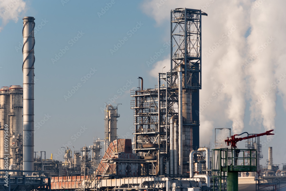 smoking chimneys of an oil refinery against blue sky