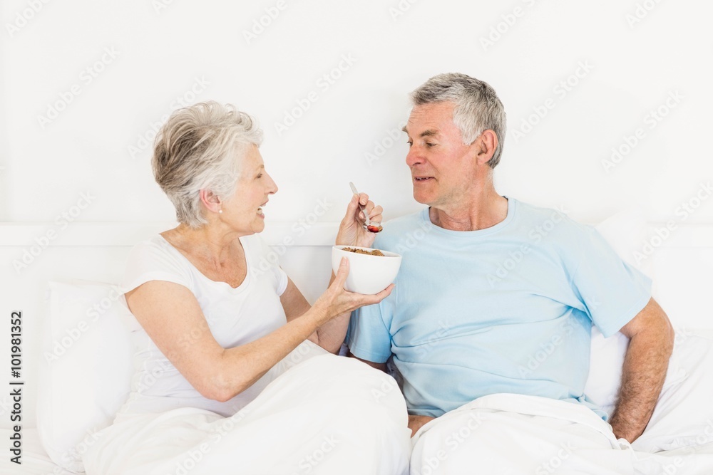 Happy senior woman feeding her husband