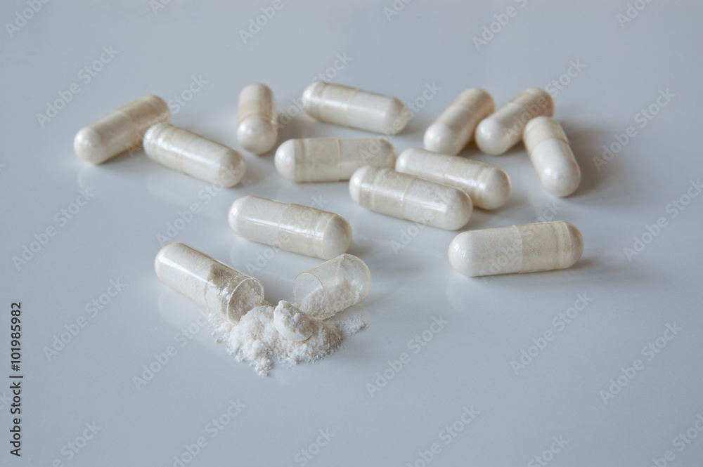 White medicine capsules with probiotic powder inside, one capsule open.  Photos | Adobe Stock