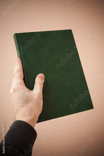 Book with empty dark green cover in male hand