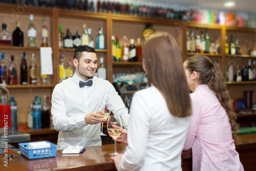 Young bartender and smiling women